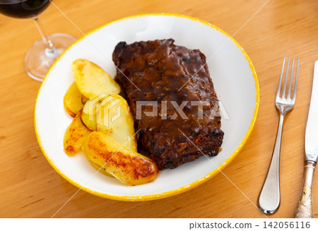Pork ribs baked under sauce, served with potatoes Pork ribs baked under sauce, served with potatoes 142056116