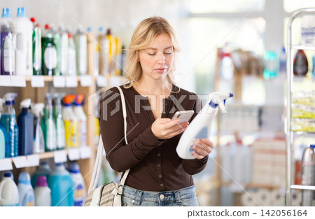Before making purchase, girl buyer scan QR code on packaging of glass cleaner spray Before making purchase, girl buyer scan QR code on packaging of glass cleaner spray 142056164