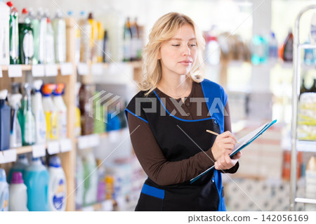 Woman seller, with papers and invoices in hands, makes inventory in store Woman seller, with papers and invoices in hands, makes inventory in store 142056169