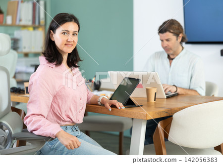 Man working on laptop and woman working on tablet in office Man working on laptop and woman working on tablet in office 142056383