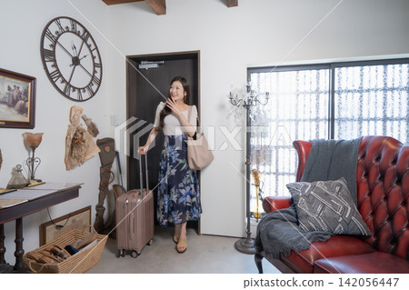 一位年輕女子拖著行李箱入住了一間時尚的度假屋。 一位年輕女子拖著行李箱入住了一間時尚的度假屋。 142056447