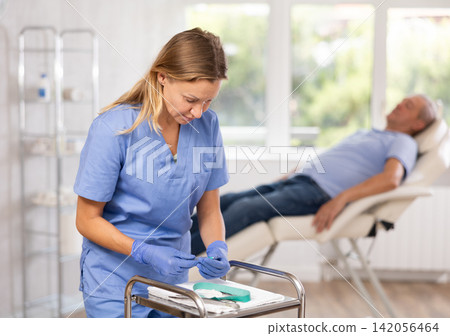 Female nurse conducts, makes necessary preparations before taking blood for analysis Female nurse conducts, makes necessary preparations before taking blood for analysis 142056464