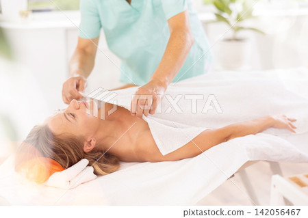 female patient under towel on massage table female patient under towel on massage table 142056467