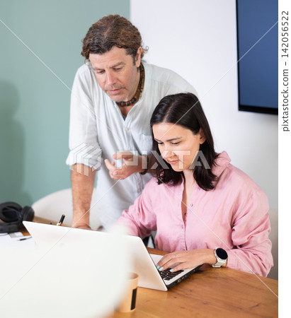 Adult man help female colleague with laptop Adult man help female colleague with laptop 142056522