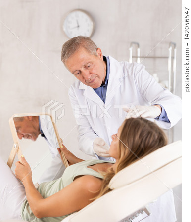 Middle-aged woman having consultation about face aesthetic while looking in the mirror Middle-aged woman having consultation about face aesthetic while looking in the mirror 142056547