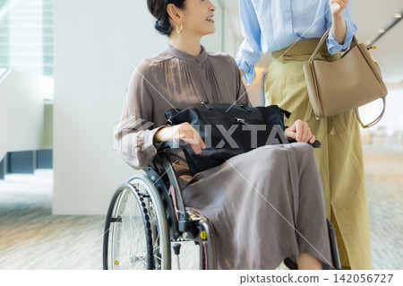 一位家長帶著孩子外出，孩子盛裝打扮，其中一人坐在輪椅上。 142056727
