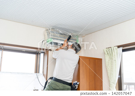 Air conditioner cleaning; a man from the air conditioner maintenance company. Air conditioner cleaning; a man from the air conditioner maintenance company. 142057047