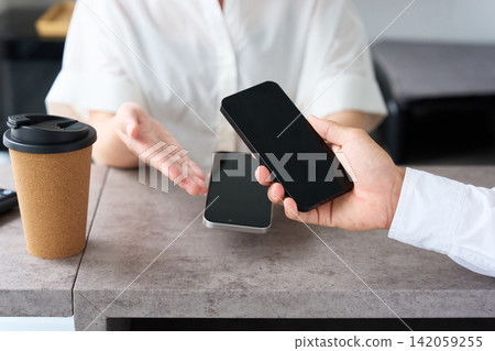 A man and a female store clerk pay using a smartphone. A man and a female store clerk pay using a smartphone. 142059255