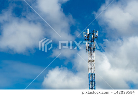 Modern telecommunication tower with cellular antennas against blue sky and clouds, wireless communication infrastructure supporting 4G, 5G mobile network, broadband internet and digital connectivity. 142059594