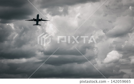 Passenger aircraft flying beneath towering storm clouds in black and white, symbolizing aviation risk, dangerous weather, turbulent skies, commercial air travel, flight safety and dramatic atmosphere. Passenger aircraft flying beneath towering storm clouds in black and white, symbolizing aviation risk, dangerous weather, turbulent skies, commercial air travel, flight safety and dramatic atmosphere. 142059665