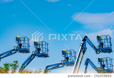 Articulated boom lift fleet with telescopic aerial work platforms against sky. Construction equipment rental, industrial maintenance, hydraulic access systems, engineering services and elevated work. Articulated boom lift fleet with telescopic aerial work platforms against sky. Construction equipment rental, industrial maintenance, hydraulic access systems, engineering services and elevated work. 142059669
