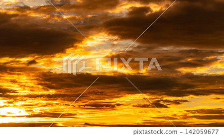 Beautiful sunset sky. Golden sunset sky with beautiful pattern of clouds. Orange, yellow, and dark clouds in the evening. Freedom and calm background. Beauty in nature. Powerful and spiritual scene. Beautiful sunset sky. Golden sunset sky with beautiful pattern of clouds. Orange, yellow, and dark clouds in the evening. Freedom and calm background. Beauty in nature. Powerful and spiritual scene. 142059677