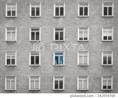 Minimal apartment building facade with repetitive windows and one blue highlighted window. Individuality, uniqueness, standing out from the crowd, urban architecture. Urban residential architecture. Minimal apartment building facade with repetitive windows and one blue highlighted window. Individuality, uniqueness, standing out from the crowd, urban architecture. Urban residential architecture. 142059700