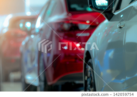 Blurred luxury red automobile inside a modern car dealership showroom. Automotive retail background. Vehicle sales, electric mobility, leasing, insurance, transportation business. Automobile industry. Blurred luxury red automobile inside a modern car dealership showroom. Automotive retail background. Vehicle sales, electric mobility, leasing, insurance, transportation business. Automobile industry. 142059754