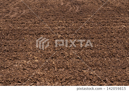 Closeup fertile agricultural soil texture prepared for crop planting, organic farmland background showing cultivated earth, natural topsoil surface, sustainable farming and agriculture concept. Closeup fertile agricultural soil texture prepared for crop planting, organic farmland background showing cultivated earth, natural topsoil surface, sustainable farming and agriculture concept. 142059815