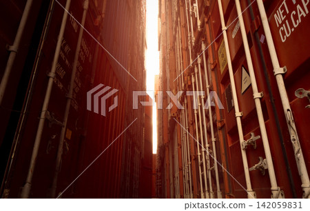 Narrow corridor between stacked shipping containers at container terminal, industrial cargo logistics infrastructure supporting global freight transportation, import export trade and supply chain. Narrow corridor between stacked shipping containers at container terminal, industrial cargo logistics infrastructure supporting global freight transportation, import export trade and supply chain. 142059831