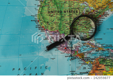 A person uses a magnifying glass to look closely at a map of the United States A person uses a magnifying glass to look closely at a map of the United States 142059877