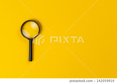 Exploring details with a magnifying glass on a bright yellow surface Exploring details with a magnifying glass on a bright yellow surface 142059919