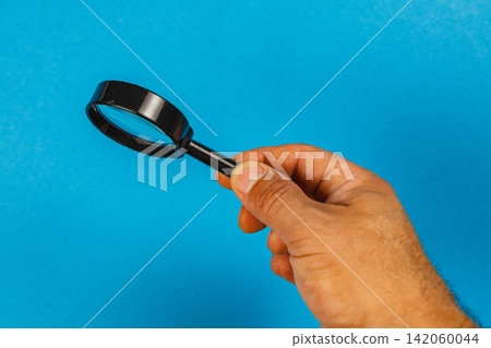 Searching with a magnifying glass in a bright blue environment Searching with a magnifying glass in a bright blue environment 142060044