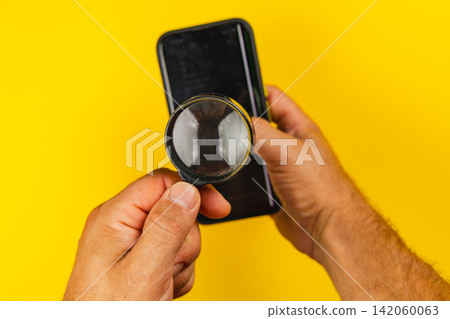 Using a magnifying glass on a smartphone screen for inspection Using a magnifying glass on a smartphone screen for inspection 142060063