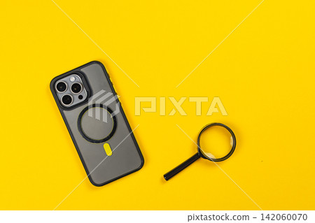 Using a smartphone with a magnifying glass on a bright yellow surface Using a smartphone with a magnifying glass on a bright yellow surface 142060070