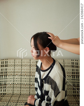 A middle school girl on summer vacation tidies up her hair in the living room of her house. A middle school girl on summer vacation tidies up her hair in the living room of her house. 142060417