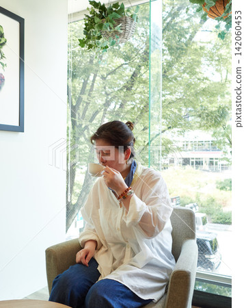 盛夏時節,一位中年女上班族在辦公大樓的休息室休息喝咖啡。 盛夏時節,一位中年女上班族在辦公大樓的休息室休息喝咖啡。 142060453