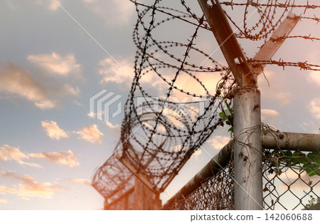 Prison security fence. Barbed wire security fence. Razor wire jail fence. Barrier border. Boundary security wall. Prison for arrest criminals or terrorists. Private area. Military zone concept. Prison security fence. Barbed wire security fence. Razor wire jail fence. Barrier border. Boundary security wall. Prison for arrest criminals or terrorists. Private area. Military zone concept. 142060688