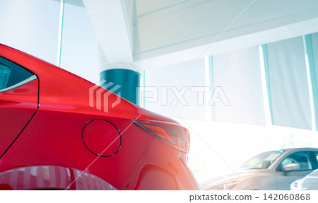 Closeup fuel tank door of red car. New and shiny luxury car parked in modern showroom for sale. Car dealership office. Electric car business concept. Automobile leasing. Automotive industry. Closeup fuel tank door of red car. New and shiny luxury car parked in modern showroom for sale. Car dealership office. Electric car business concept. Automobile leasing. Automotive industry. 142060868