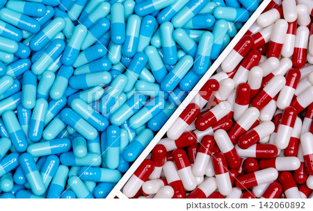 Top view of blue capsules and red-white capsules pills in a plastic tray. Full frame of two drugs. Pharmacy drugstore products. Pharmacology concept. Healthcare and medicine. Pharmaceutical industry. 142060892