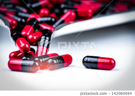 Selective focus of red and black capsule pills on stainless steel drug tray. Antibiotics drug resistance. Global healthcare. Antimicrobial capsule pills. Pharmacy background. Health budgets and policy Selective focus of red and black capsule pills on stainless steel drug tray. Antibiotics drug resistance. Global healthcare. Antimicrobial capsule pills. Pharmacy background. Health budgets and policy 142060894
