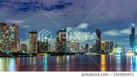 Panoramic Bangkok skyline at night along the Chao Phraya River in Thailand with illuminated skyscrapers, colorful reflections, modern waterfront architecture and iconic city landmarks. Panoramic Bangkok skyline at night along the Chao Phraya River in Thailand with illuminated skyscrapers, colorful reflections, modern waterfront architecture and iconic city landmarks. 142060955