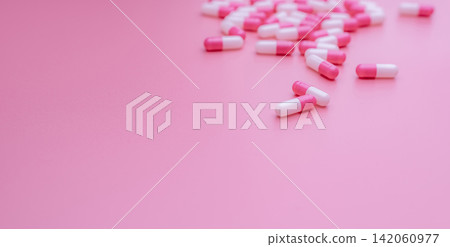 Pink-white antibiotic capsule pills on pink background. Antibiotic drug resistance, overuse, and misuse concept. Pharmaceutical industry. Prescription drugs. Pills for love and happiness. Healthcare. Pink-white antibiotic capsule pills on pink background. Antibiotic drug resistance, overuse, and misuse concept. Pharmaceutical industry. Prescription drugs. Pills for love and happiness. Healthcare. 142060977