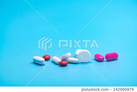 White and pink tablets pills on blue background. Pharmacy banner. Pharmaceutical industry. Health insurance strategy. Pharmaceutical manufacturing. Tablets pills production topics. Drug selection. White and pink tablets pills on blue background. Pharmacy banner. Pharmaceutical industry. Health insurance strategy. Pharmaceutical manufacturing. Tablets pills production topics. Drug selection. 142060979