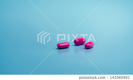 Pink tablets on blue background. Painkiller medicine. Ibuprofen tablets pills. Pharmaceutical industry. Drug for treatment migraine headache. Community pharmacy product. Cancer pain management concept Pink tablets on blue background. Painkiller medicine. Ibuprofen tablets pills. Pharmaceutical industry. Drug for treatment migraine headache. Community pharmacy product. Cancer pain management concept 142060981