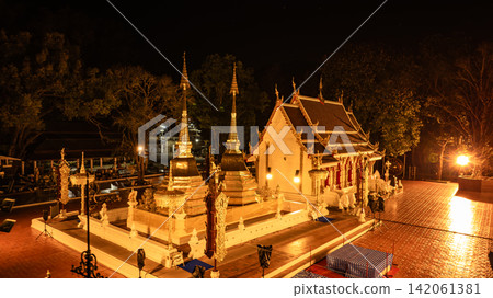 Doi Tung summit reveals a sacred golden Thai temple illuminated at night, traditional Buddhist architecture, cultural heritage, and radiant golden light in a 2023 aerial view. Doi Tung summit reveals a sacred golden Thai temple illuminated at night, traditional Buddhist architecture, cultural heritage, and radiant golden light in a 2023 aerial view. 142061381