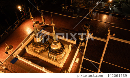 Aerial view of Phra That Doi Tung in Chiang Rai, Thailand, illuminated by warm golden lights at night in 2023. 142061389