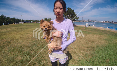 A cute child playing with a dog at a beach in the summer. A cute child playing with a dog at a beach in the summer. 142061419