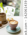 Cup of hot latte coffee on table by the window. 142061439