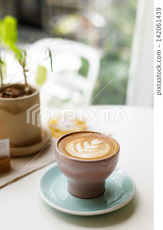 Cup of hot latte coffee on table by the window. Cup of hot latte coffee on table by the window. 142061439