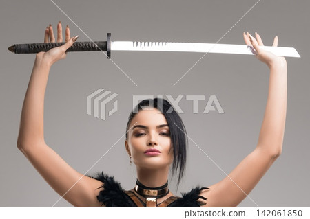 Woman holds modern sword above her head in Studio Woman holds modern sword above her head in Studio 142061850