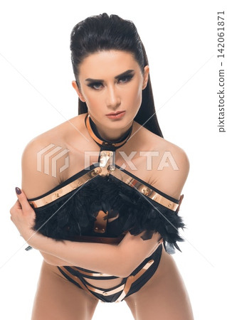 Model showcases bold fashion with feathers and straps in expressive pose Model showcases bold fashion with feathers and straps in expressive pose 142061871