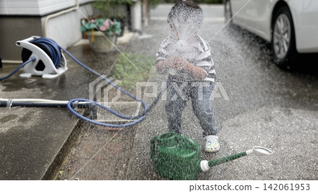 孩子們在玩從軟管噴出的水。 孩子們在玩從軟管噴出的水。 142061953