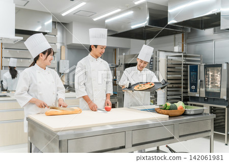 Chefs and cooks in chef coats standing in the kitchen Chefs and cooks in chef coats standing in the kitchen 142061981