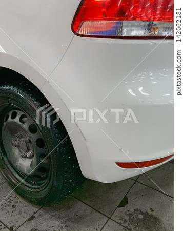 White car rear bumper wheel arch with minor paint scratch and dent parked in indoor parking garage White car rear bumper wheel arch with minor paint scratch and dent parked in indoor parking garage 142062181
