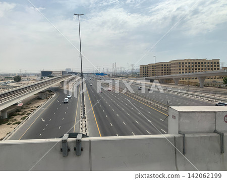 A high angle view of a wide multi lane highway with cars driving past a metro train line in a modern city A high angle view of a wide multi lane highway with cars driving past a metro train line in a modern city 142062199