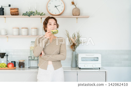女人在廚房檯面上喝排毒水 女人在廚房檯面上喝排毒水 142062410
