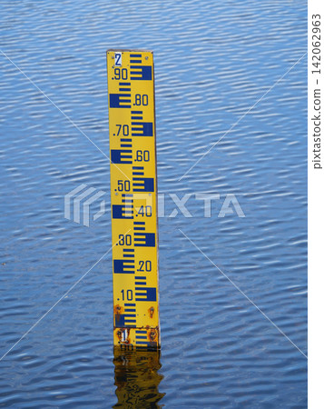 Yellow water level gauge or staff Gauge with alphabet number with reflection on the blue water surface Yellow water level gauge or staff Gauge with alphabet number with reflection on the blue water surface 142062963