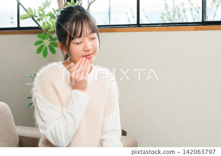小學和國中女生因為嘴唇疼痛而摀住嘴 小學和國中女生因為嘴唇疼痛而摀住嘴 142063797