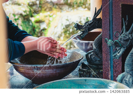 信徒們在神社的淨手池旁，用從龍形噴頭流出的水潔淨雙手。 142063885